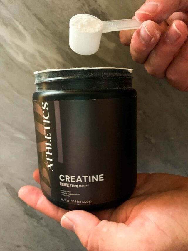This is a picture of a jar of creatine. This is a hand holding a scoop of the creatine