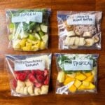 This is a picture of 4 pre-made smoothie meal prep bags. Each bag has smoothie ingredients like fruits, greens, and protein powder. The title of each smoothie is written on the bag. There is one for green, chocolate peanut butter, strawberry banana, and tropical.