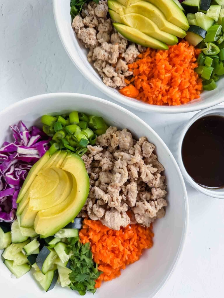 Close up of two spring roll bowls and sauce