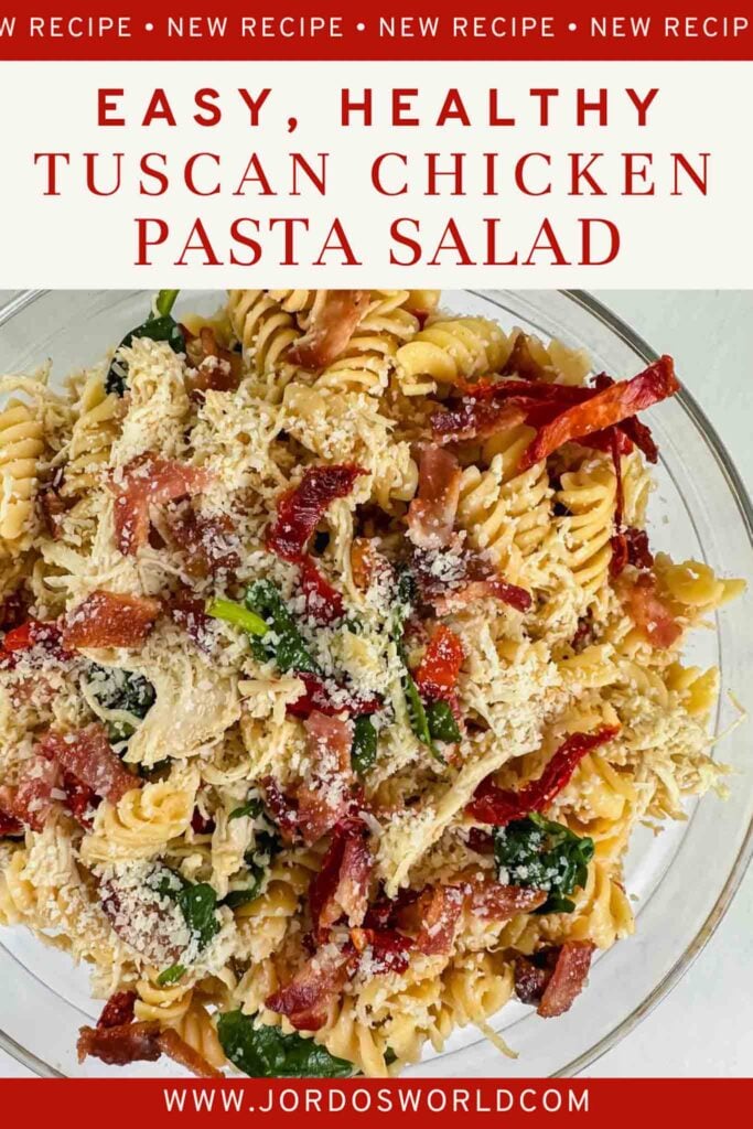 This is a pinterest pin for tuscan chicken pasta salad. There is a clear glass bowl filled with pasta, shredded chicken, spinach, dried tomatoes, bacon, and cheese. Everything is mixed together and the title of the recipe is above the image.