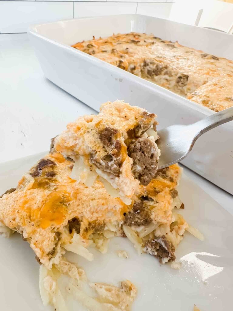 Forkful of breakfast hashbrown casserole with plate and dish