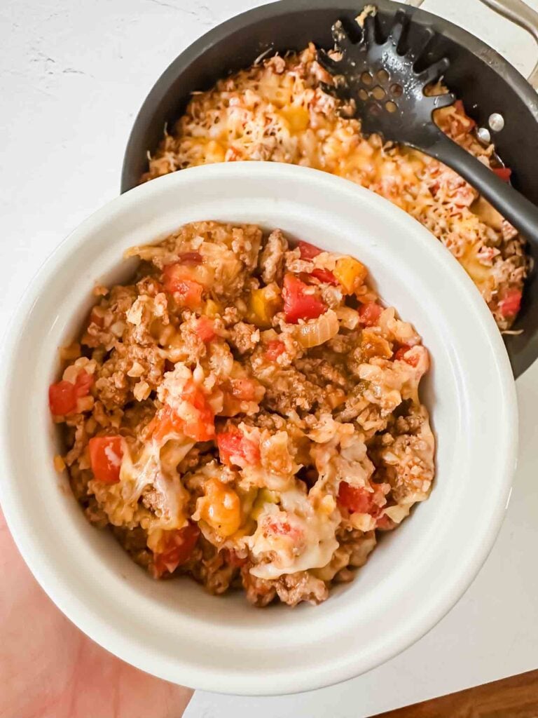 Bowl with single serving of mexican cauliflower rice with skillet in background