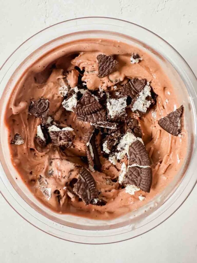This is a picture of chocolate protein ice cream. There's a creami base with smooth, creamy chocolate ice cream topped with crushed oreo cookie pieces.