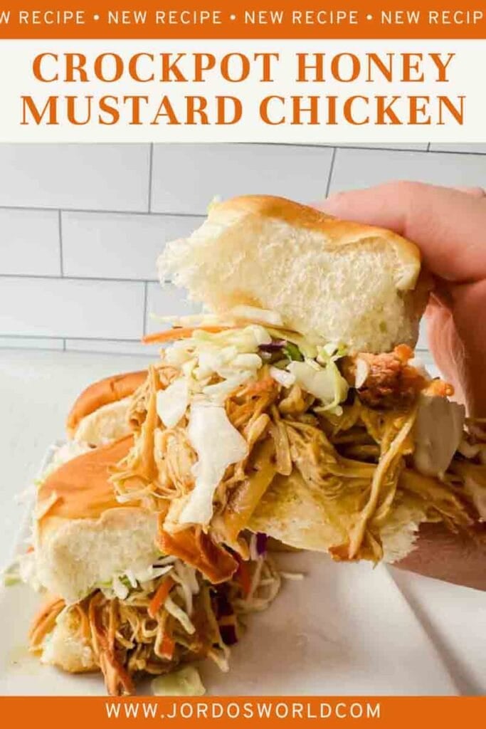 This is a pinterest pin of crockpot honey mustard chicken. This is a picture of honey mustard sliders. There's a white plate holding sliders that have shredded chicken and slaw on buns. A hand is holding up a honey mustard chicken slider.