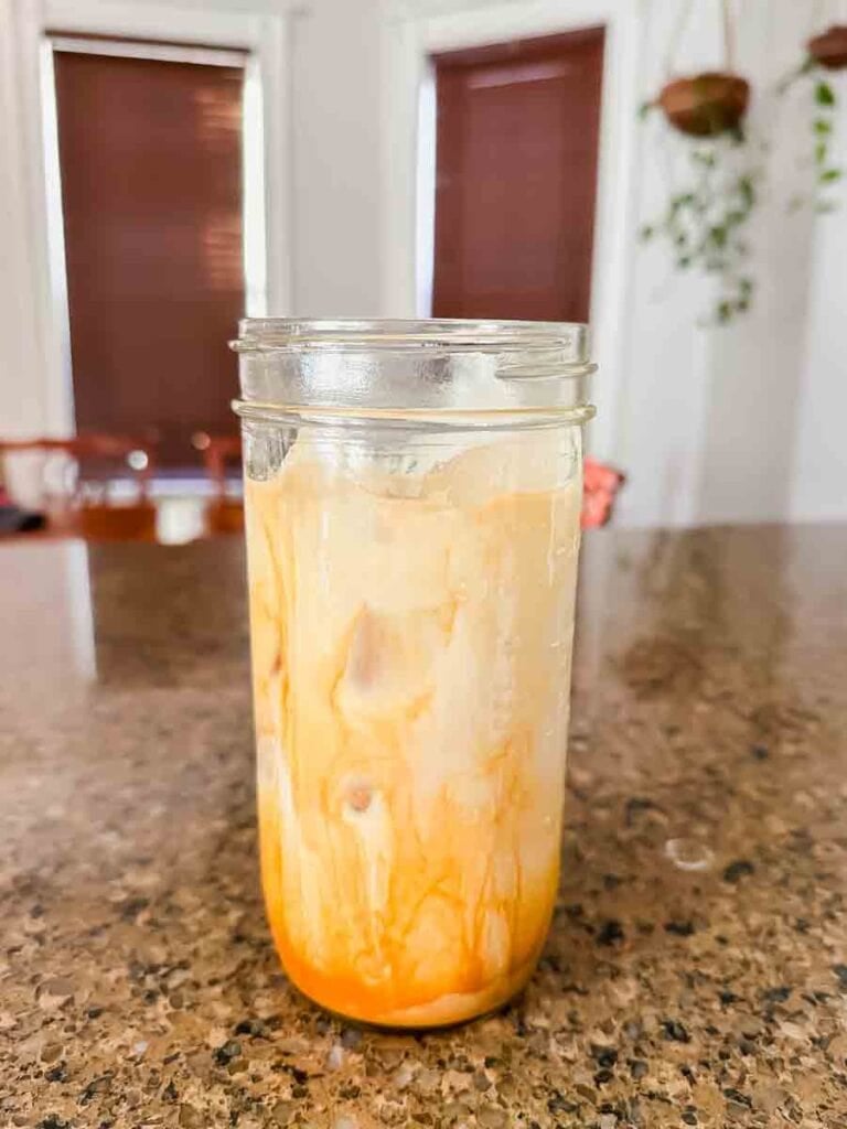 This is a picture of an iced sf latte. There's a glass mason jar filled with a light brown latte that's mixing together.