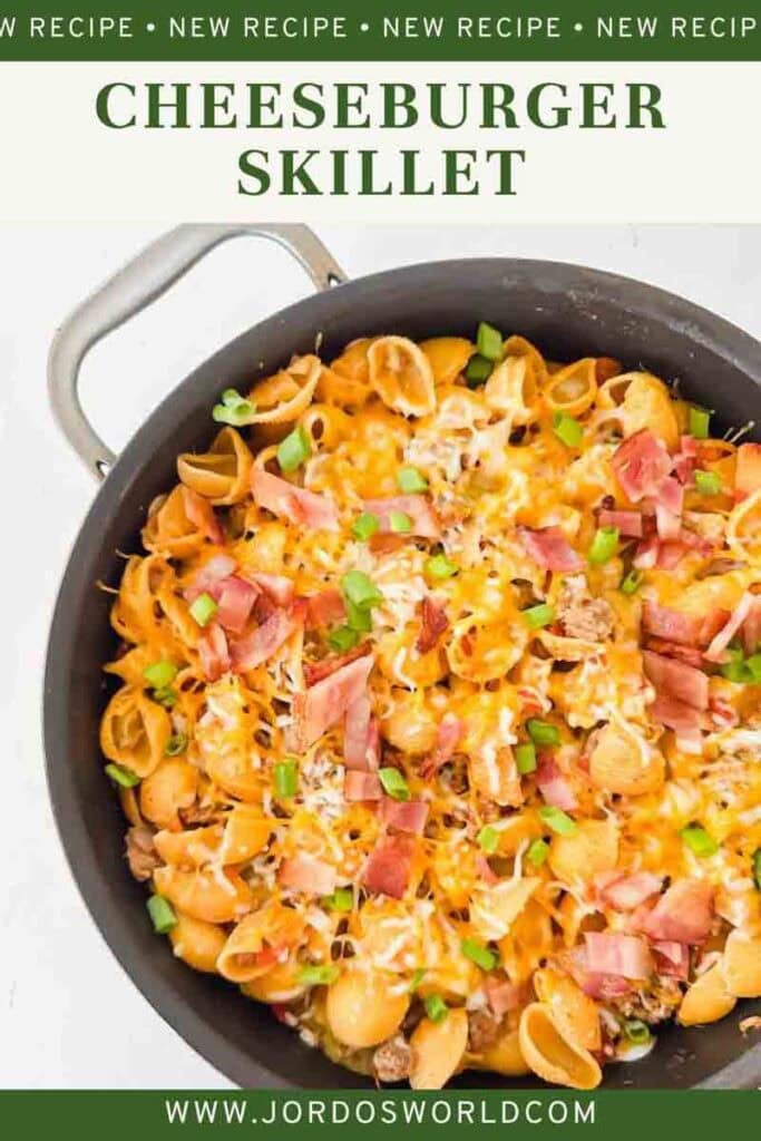 Cheesy pasta with bacon, green onions, and cheese in a large black skillet. This is bacon cheeseburger skillet.