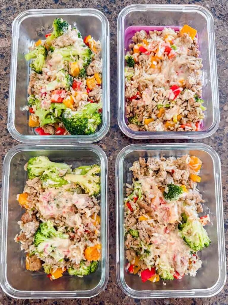 This is meal prep containers of bang bang turkey rice bowls. Each container has ground turkey, rice, broccoli, bell peppers, and a yummy sauce on top.