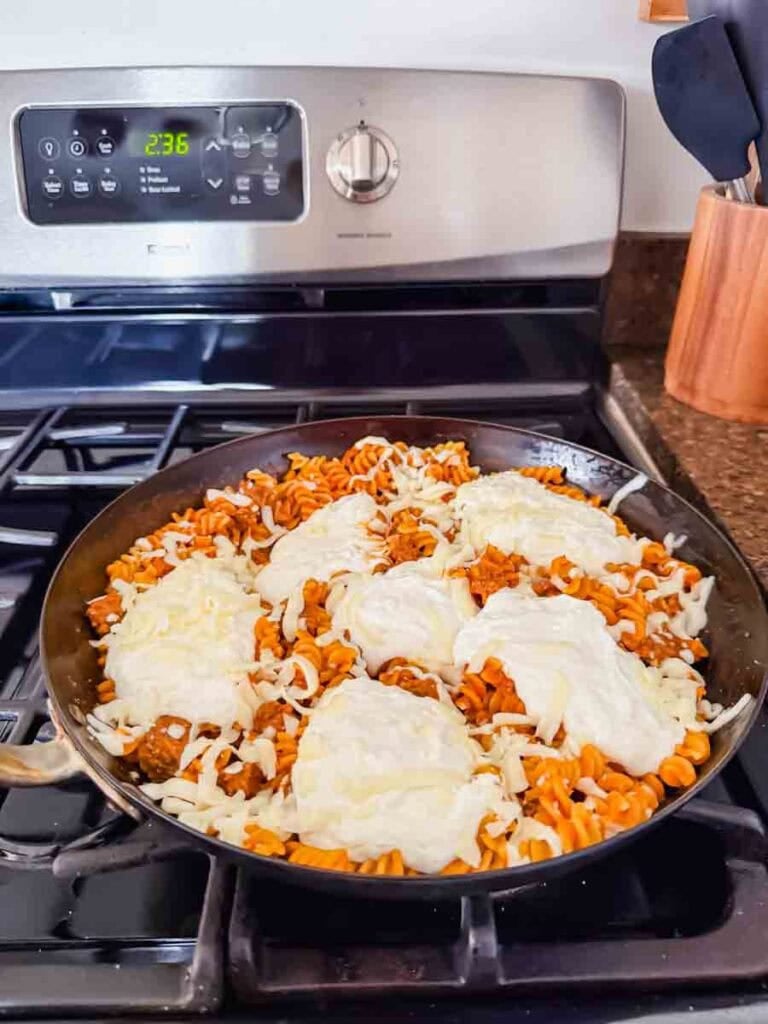 There is a large skillet of pumpkin pasta topped with dollops of high-protein cheese.